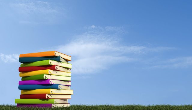 books-piled-in-front-of-blue-sky-istock-2048x1180