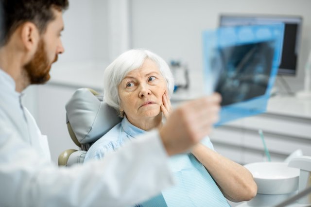Dentist showing x-ray to the elder woman in the dentall office