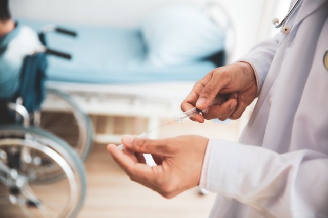 doctor-preparing-syringe-injection-for-disabled-patient-at-hospital-picture-id1262877425