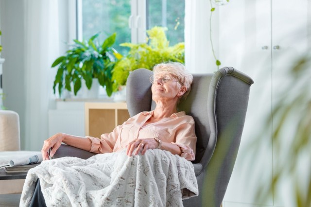 Elderly lady resting in an armchair in her room