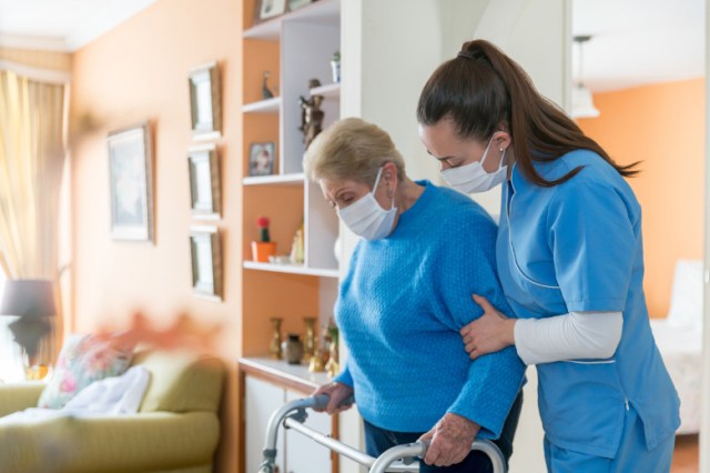 home-caregiver-wearing-a-facemask-while-assisting-a-senior-woman-a-picture-id1282348252