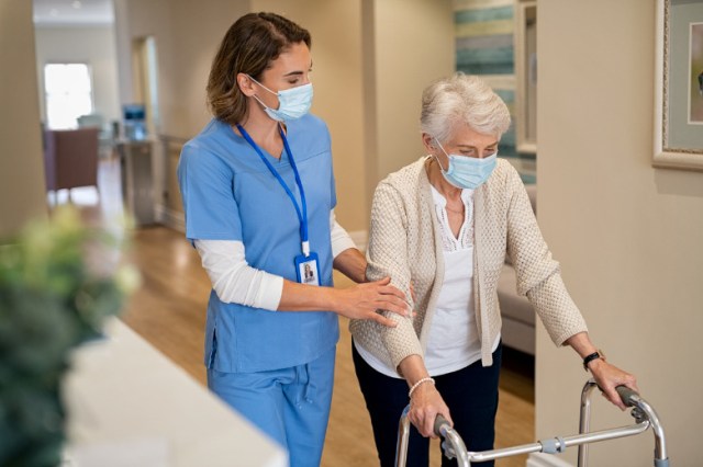 nurse-helping-senior-woman-walk-at-nursing-home-picture-id1307369109