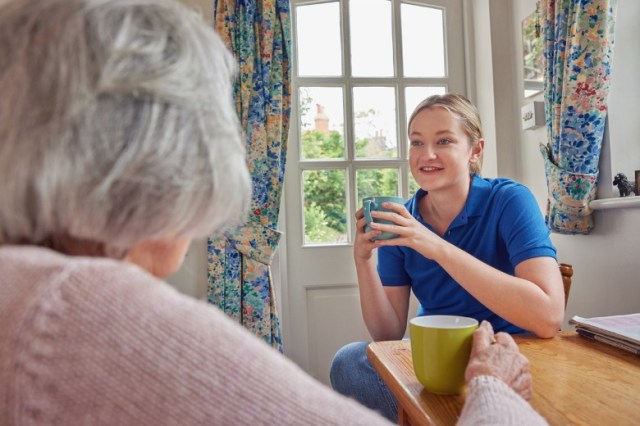 female-home-help-having-cup-of-tea-with-lonely-senior-woman-in-picture-id1327446880