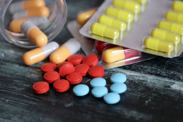 pills-and-capsules-in-blister-pack-and-bottle-on-dark-wooden-table-picture-id1152203986