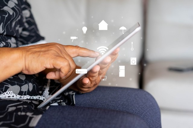 close up senior woman holding digital tablet and using wifi technology to home automation function for looking and monitor inside or outside home and property , mature life and ai innovation future concept