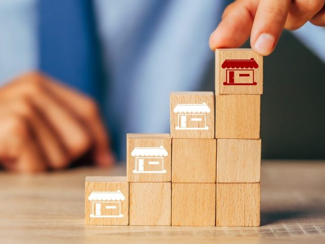 Cubes wood Franchise business,Businessman hand choose wooden blog with franchise marketing store icons.Franchise business concept.